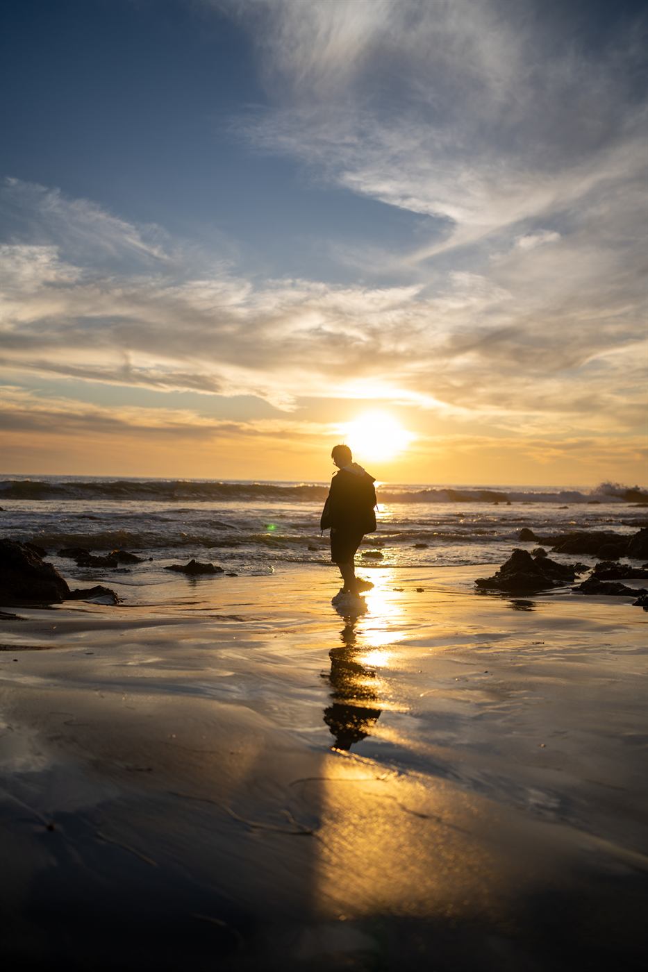 Silhouette walking along Crystal Cove at sunset